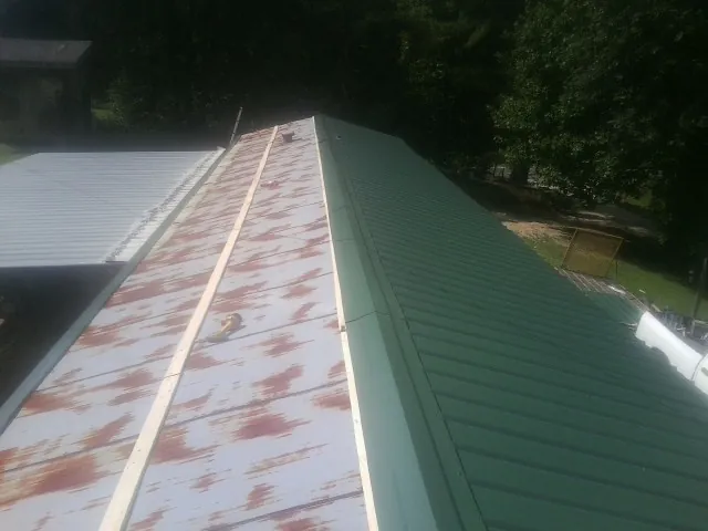 Old rusted panels beside newly installed green metal roofing — Wind Damage Roof Repair by Roofing Brothers in Forsyth